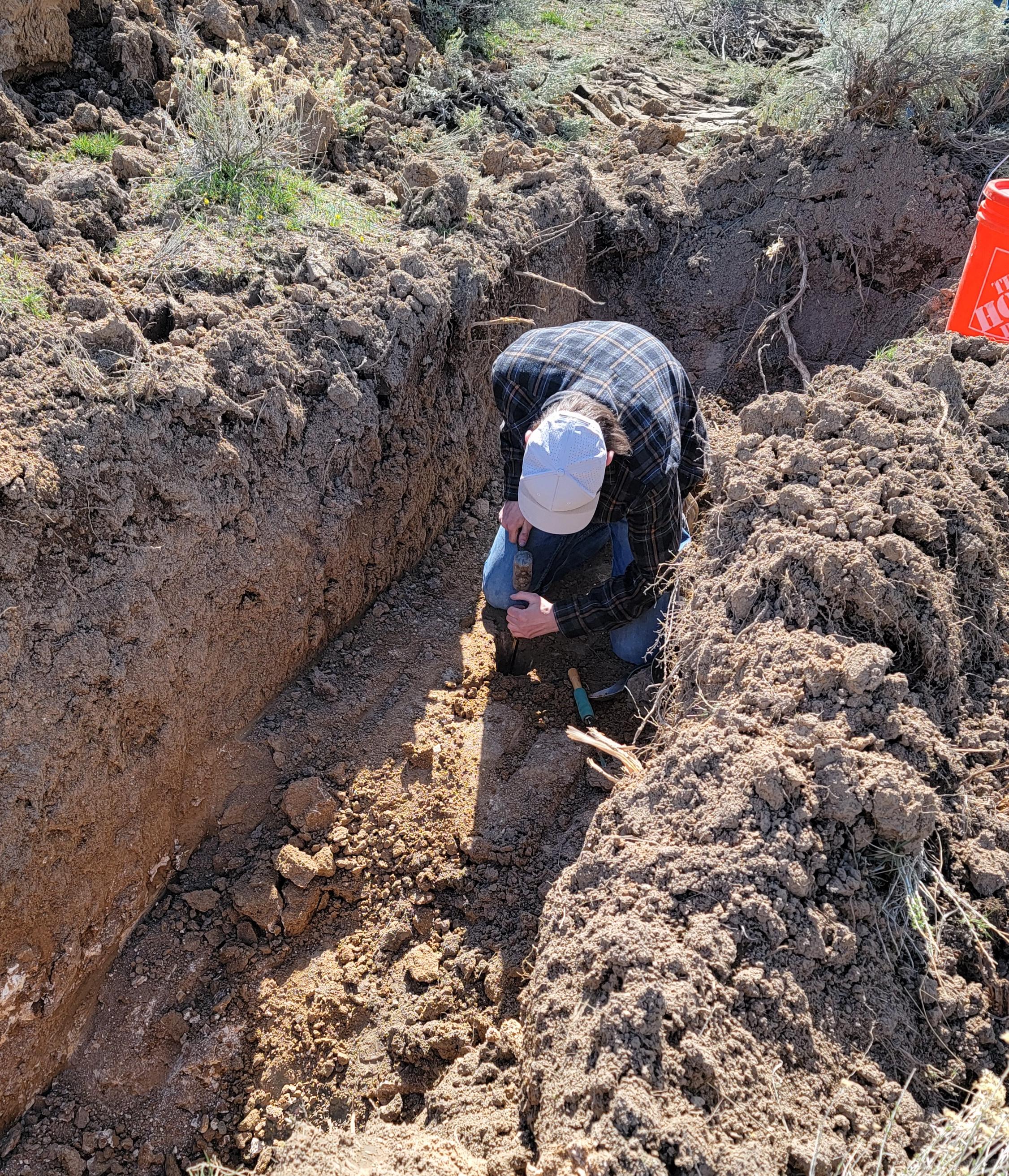 Technician using hand tools to dig a percolation test hole.